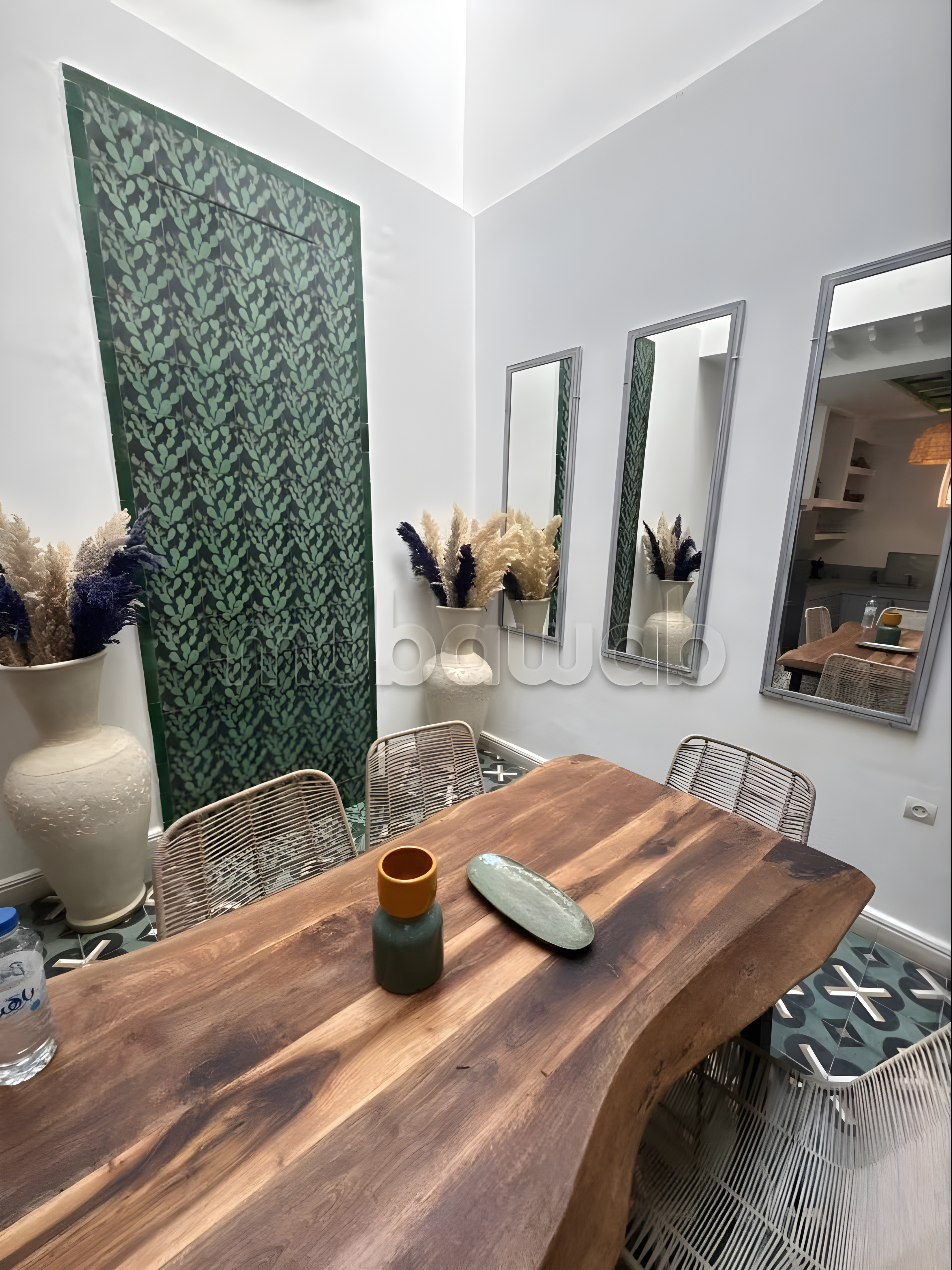 Guesthouse kitchen in Sidi Bou Amar with wooden table, chairs, mirrors, and decorative vases.