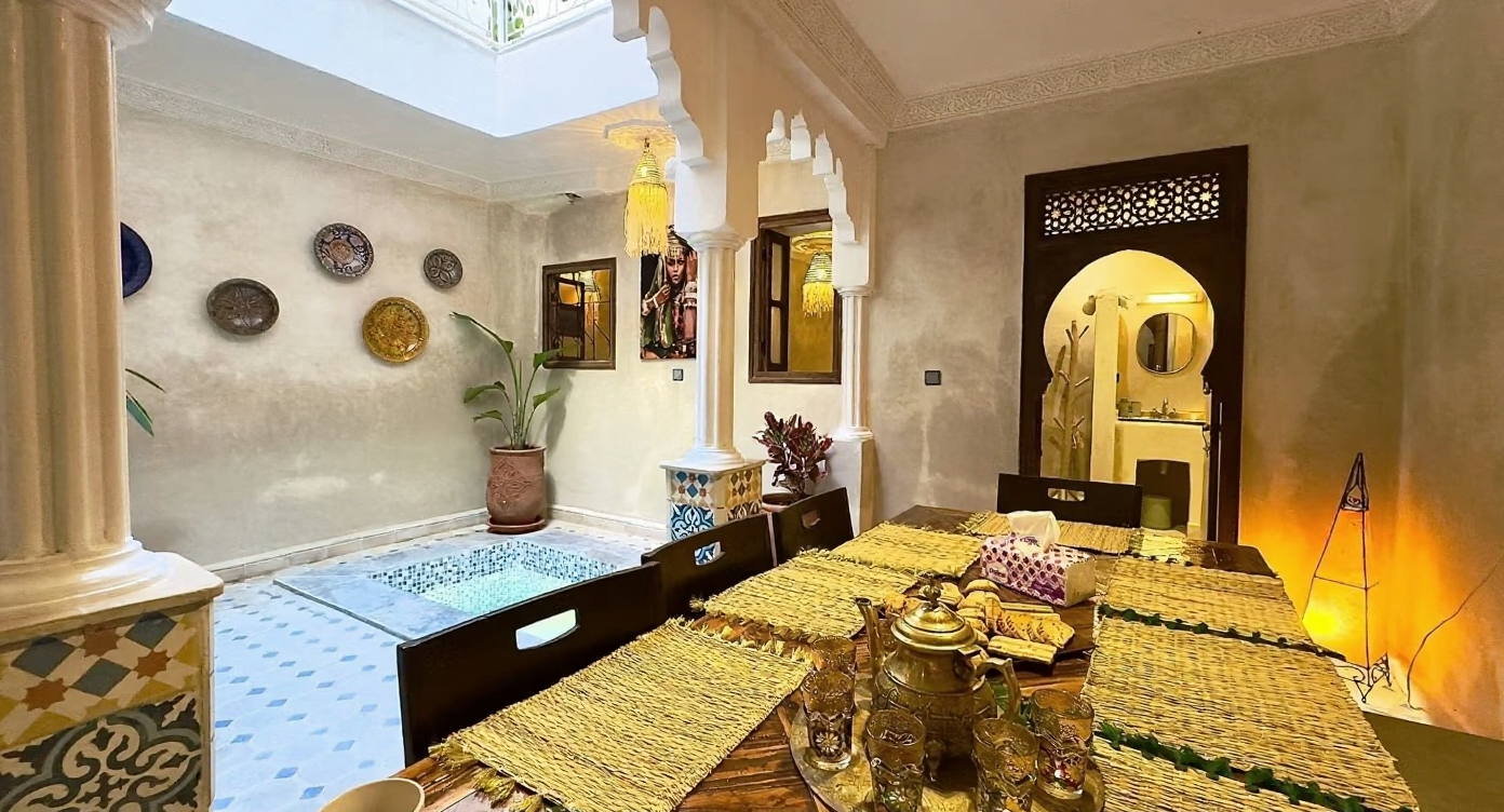 Traditional Moroccan patio with arches, water feature, and dining setup in Bab Aylan.