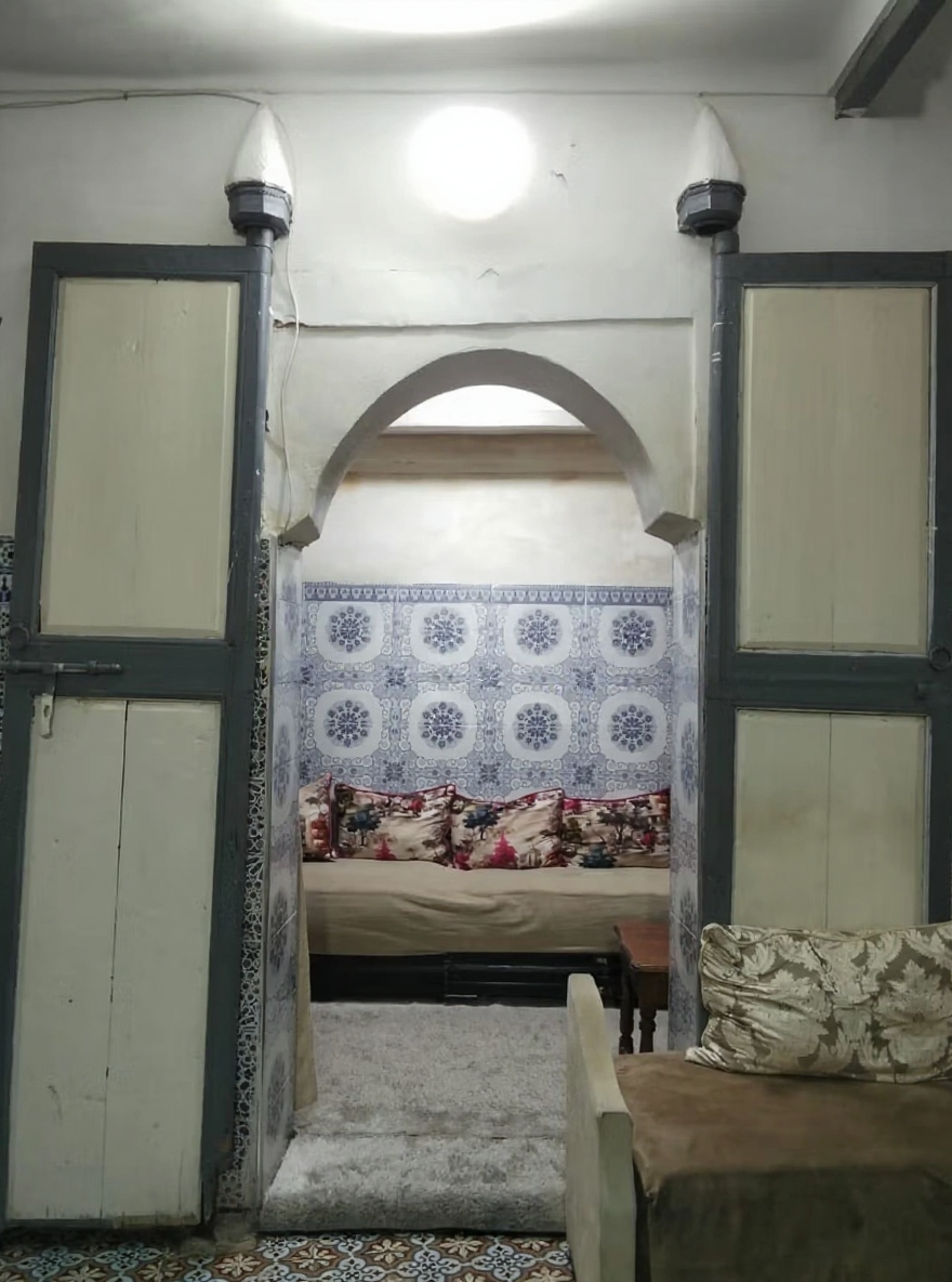 Traditional bedroom in a Moroccan riad with tiled walls and arched entryway in Kaat Ben Nahid.