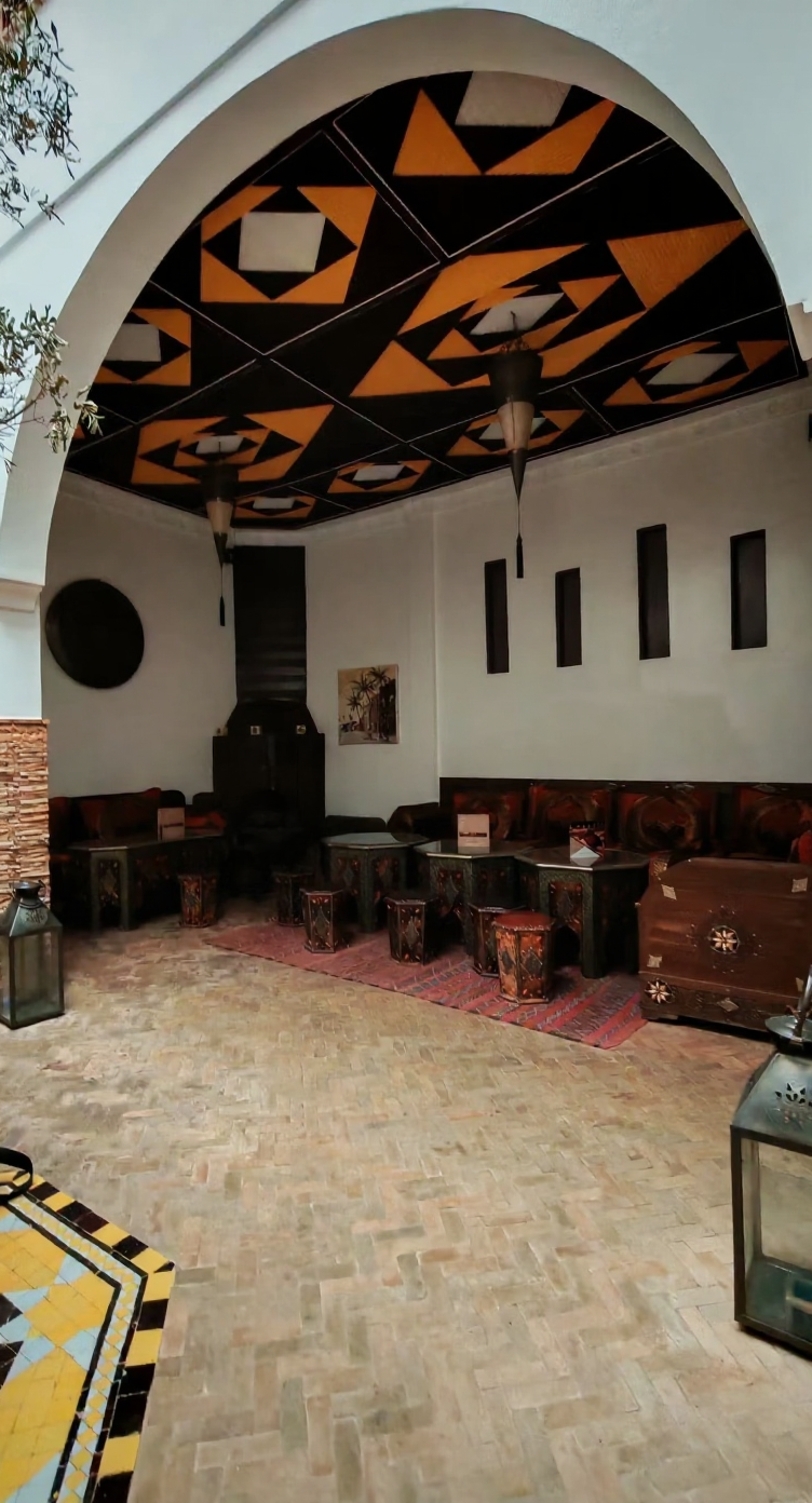 Moroccan-style guesthouse patio in Rmila with wooden furniture and geometric ceiling.