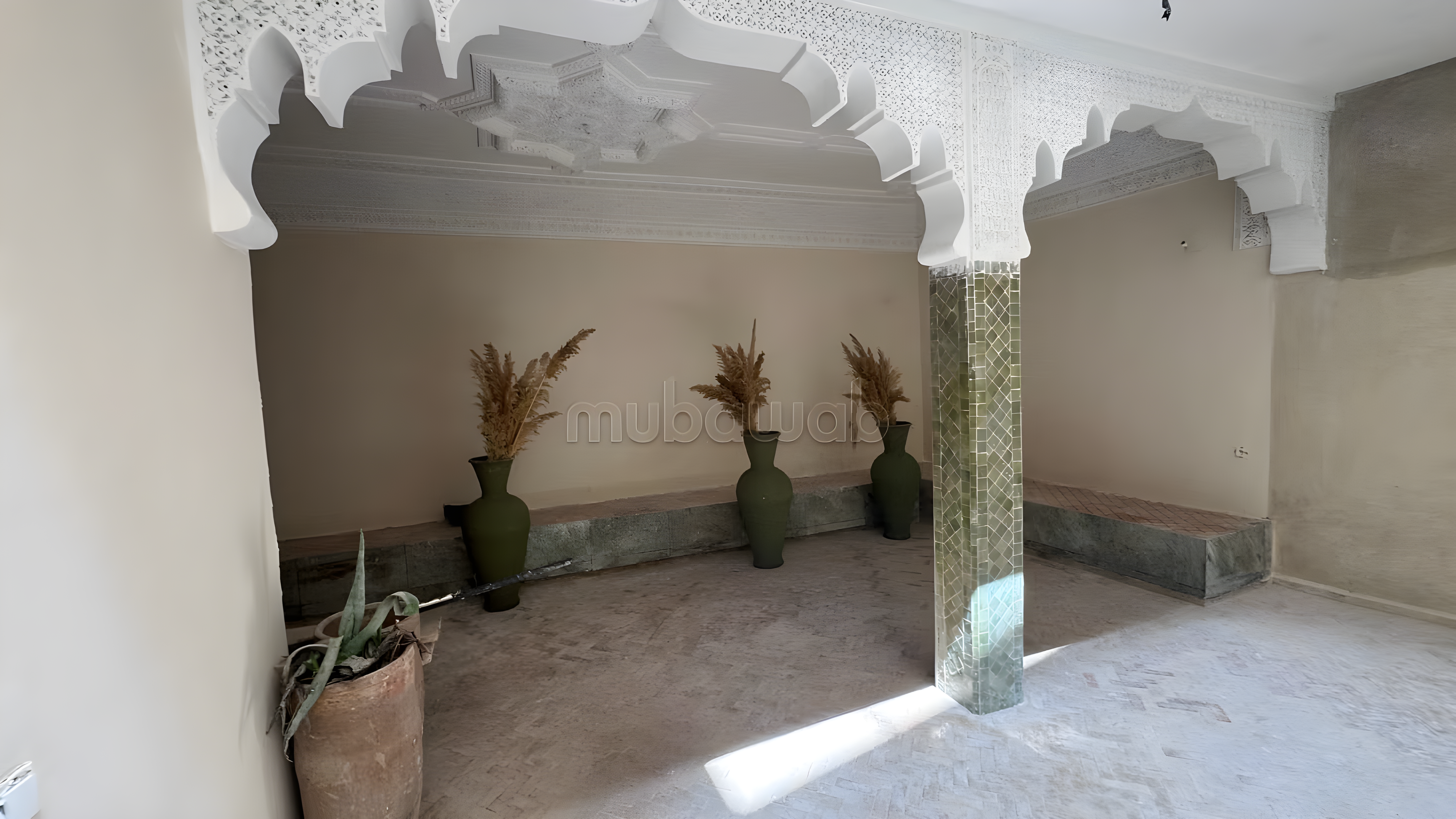Elegant salon in Rahba Kedima guesthouse with arches and tiled columns.