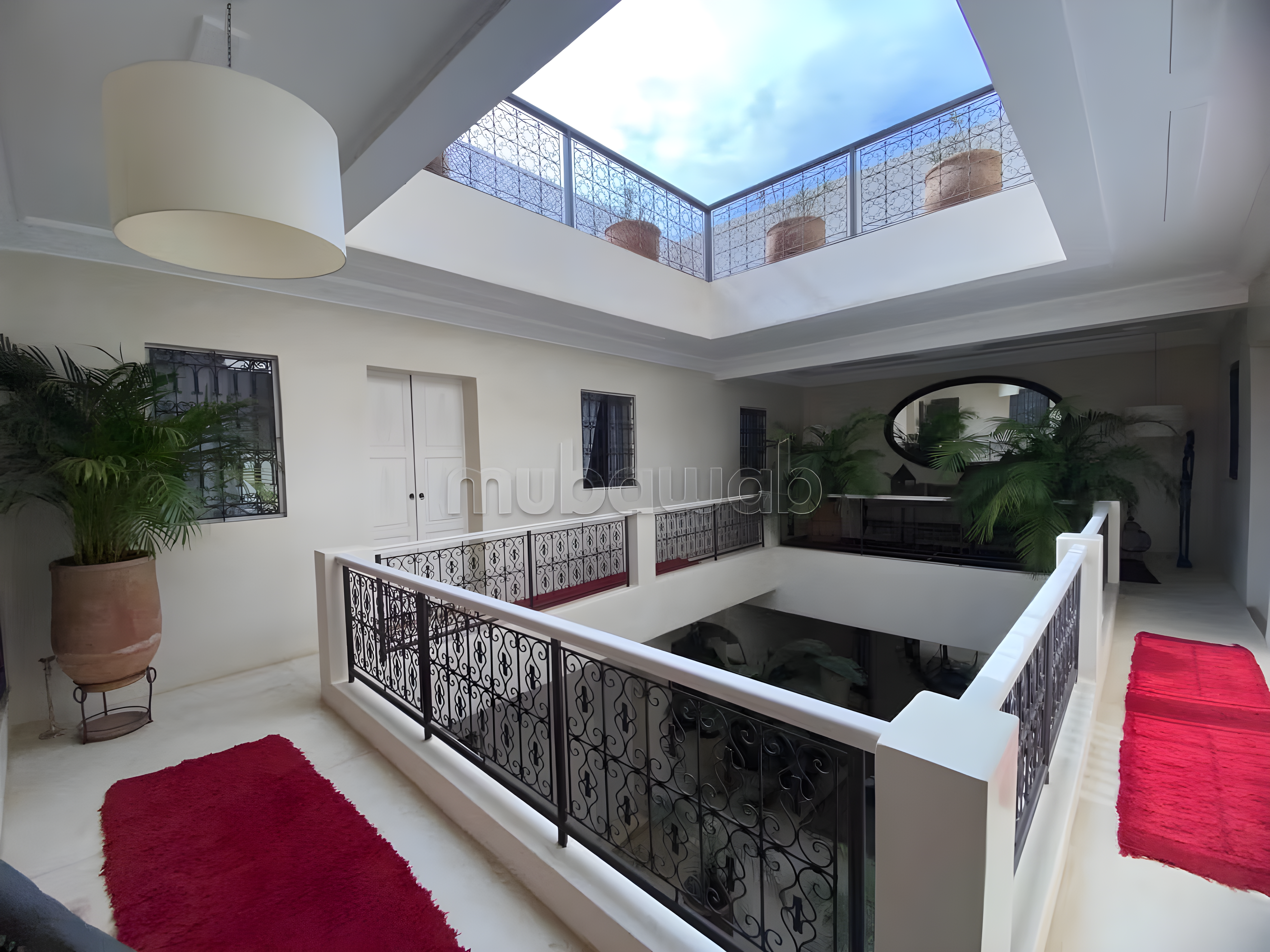 Open-air courtyard with plants and decorative railings in Moulay Lyazid guesthouse.