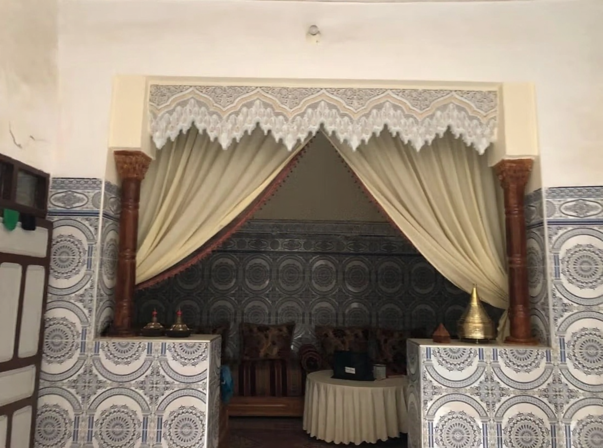 Traditional Moroccan salon in Kaat Ben Nahid with patterned tiles and wooden columns.