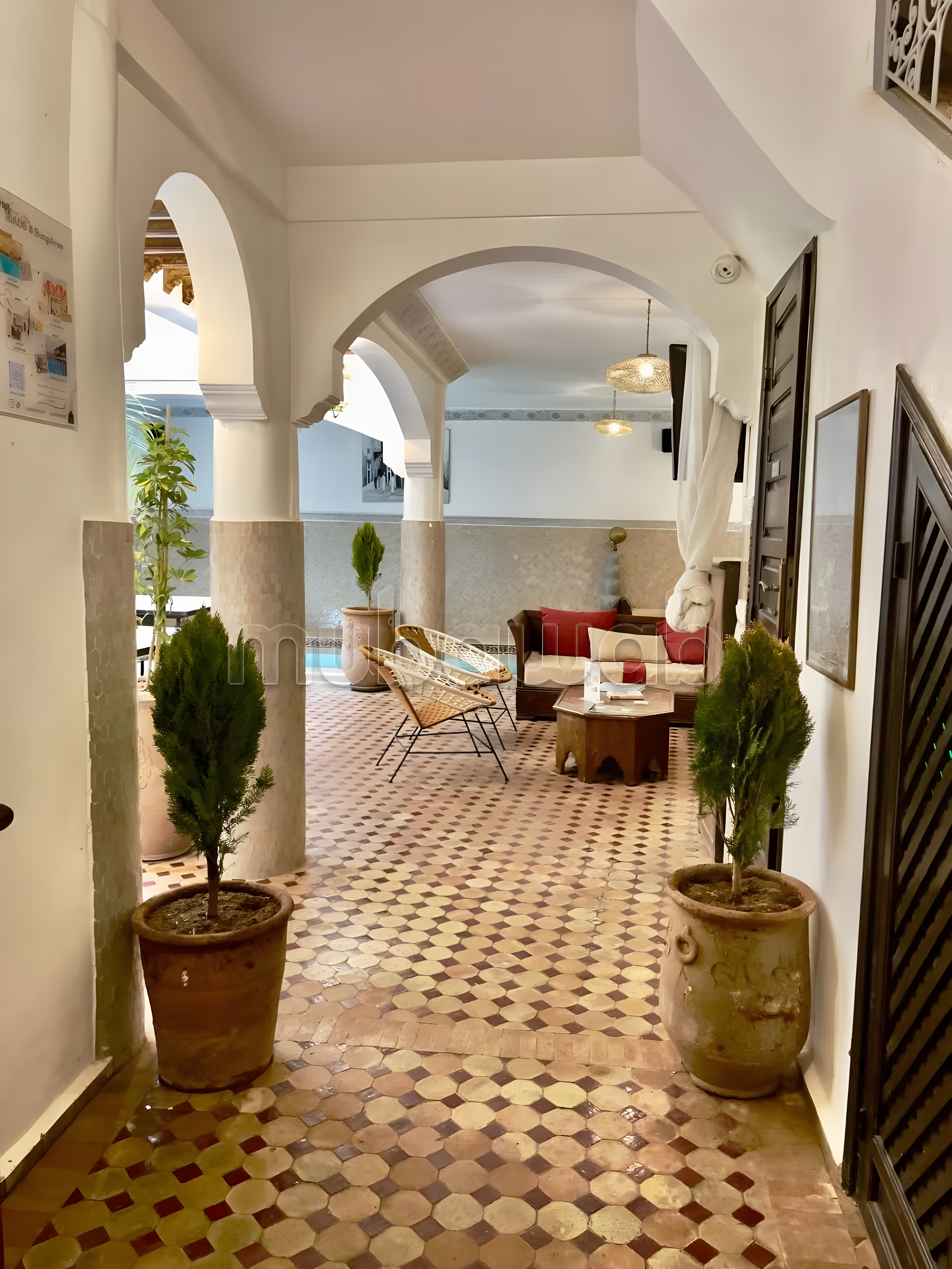 Covered patio with Moroccan tiles, archways, and plants in a Kennaria guesthouse.