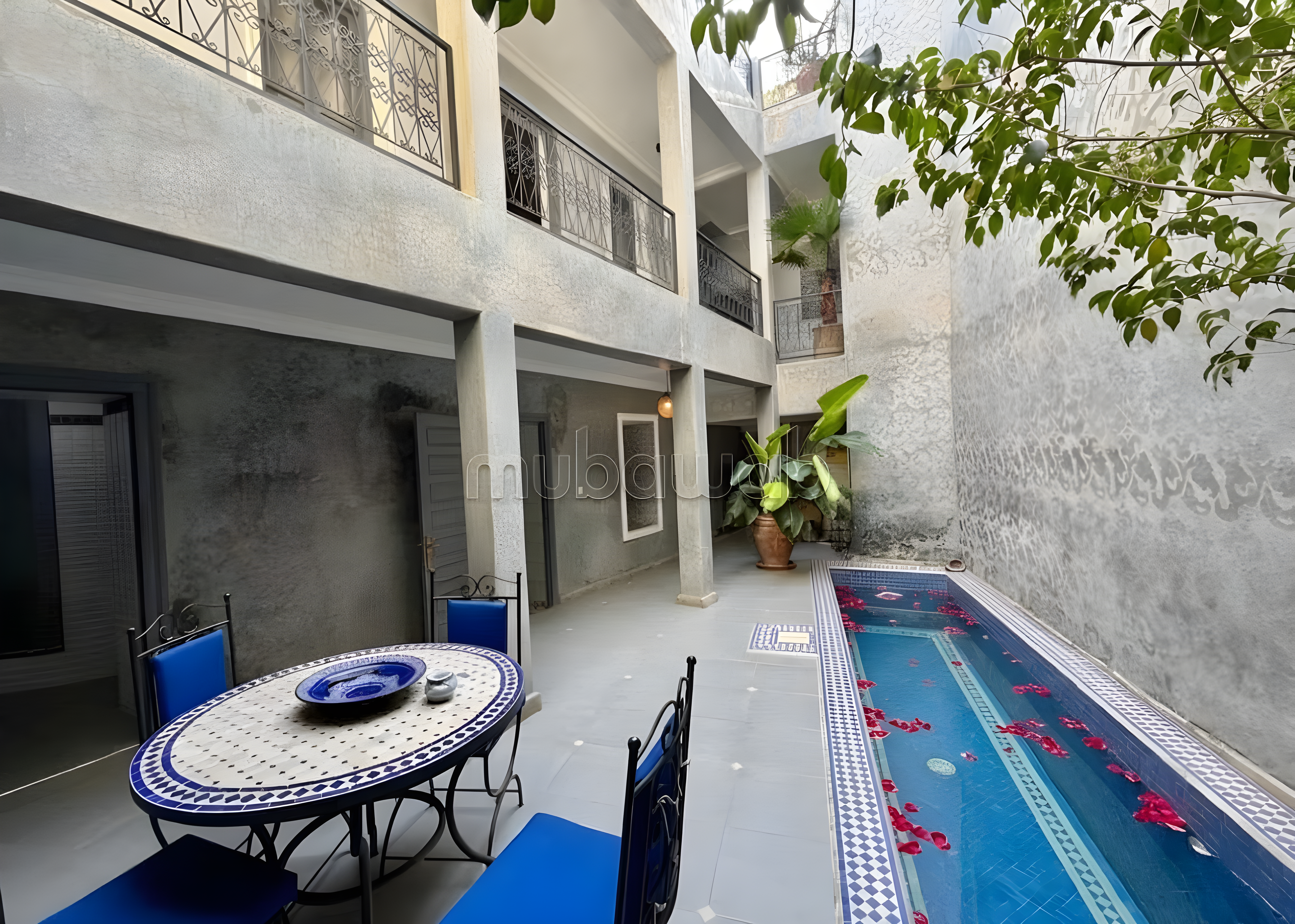 Courtyard with pool, floral decor, tiled tables, and balconies in Arset Ben Chebli guesthouse.