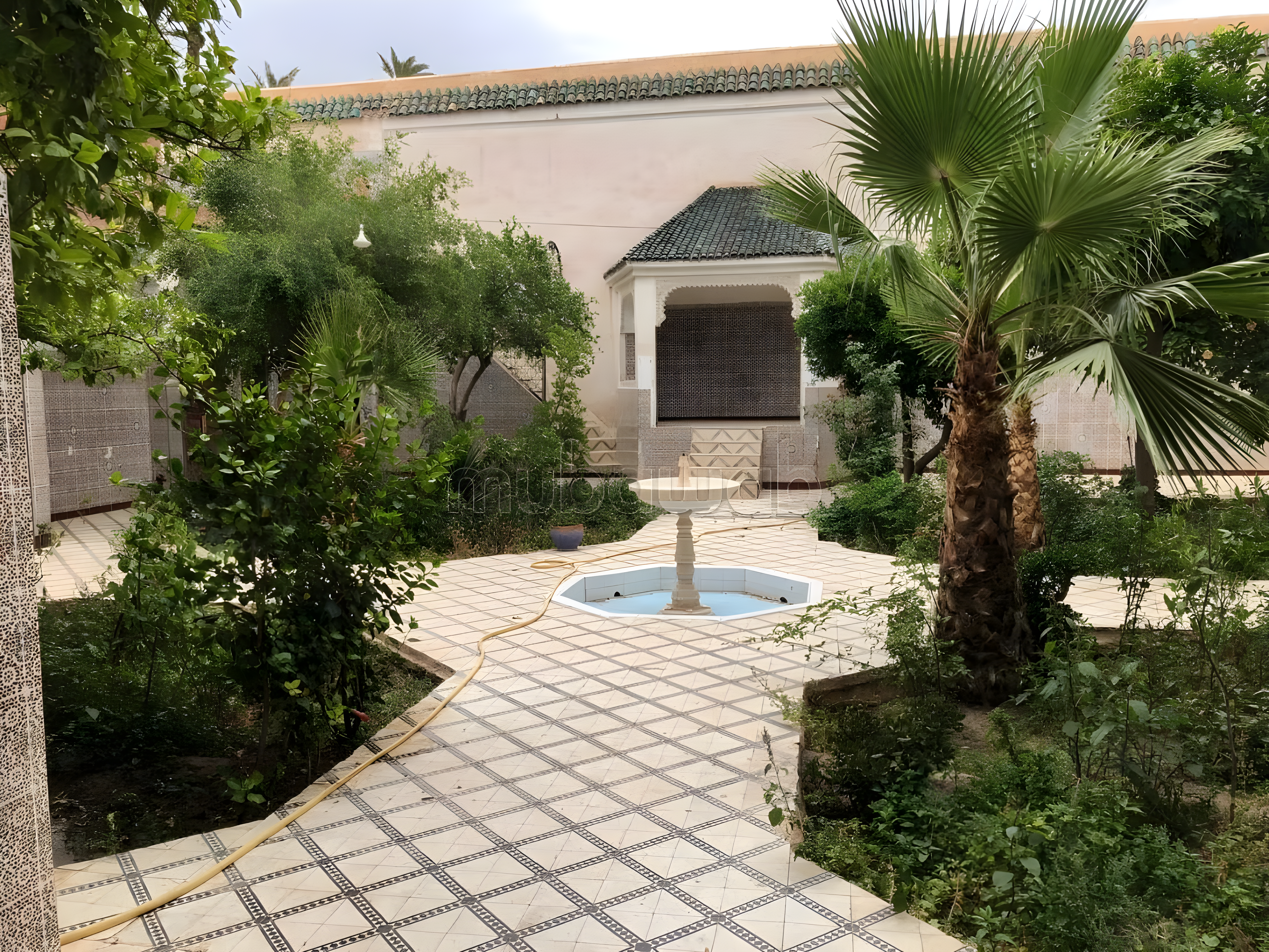 Courtyard with tile flooring, fountain, greenery, and shaded seating in Arset Ihiri guesthouse.