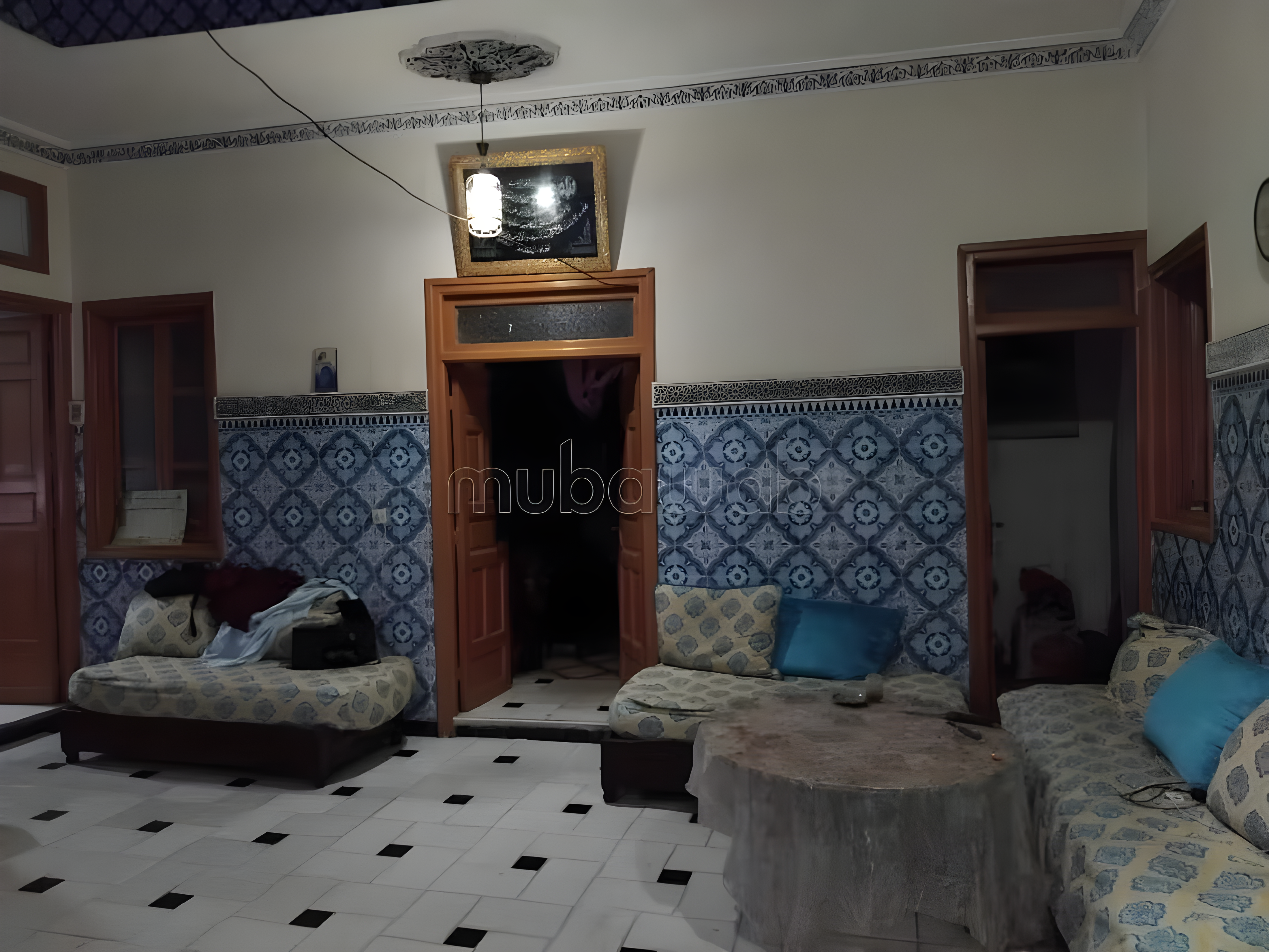 Moroccan salon in Kennaria with tile walls, cushions, and a central table.