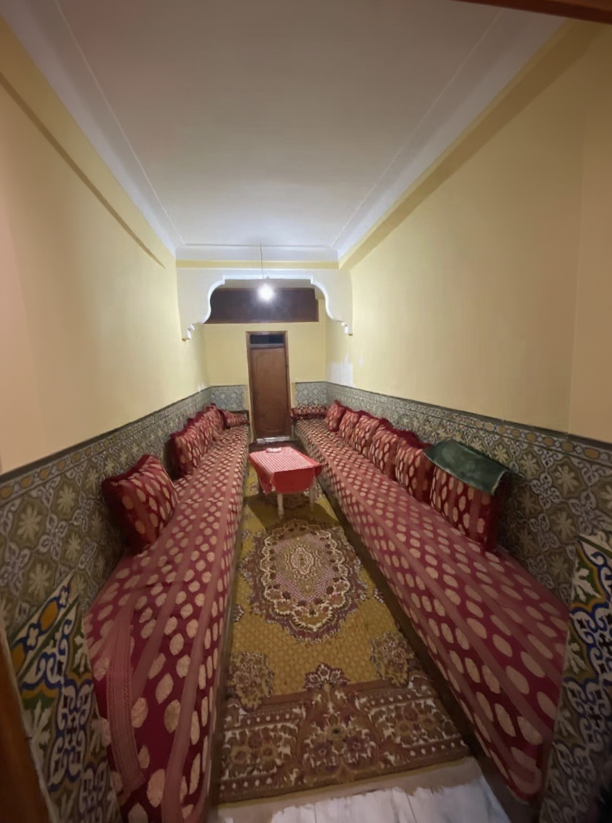 Traditional Moroccan salon with red curtains and tiled walls.