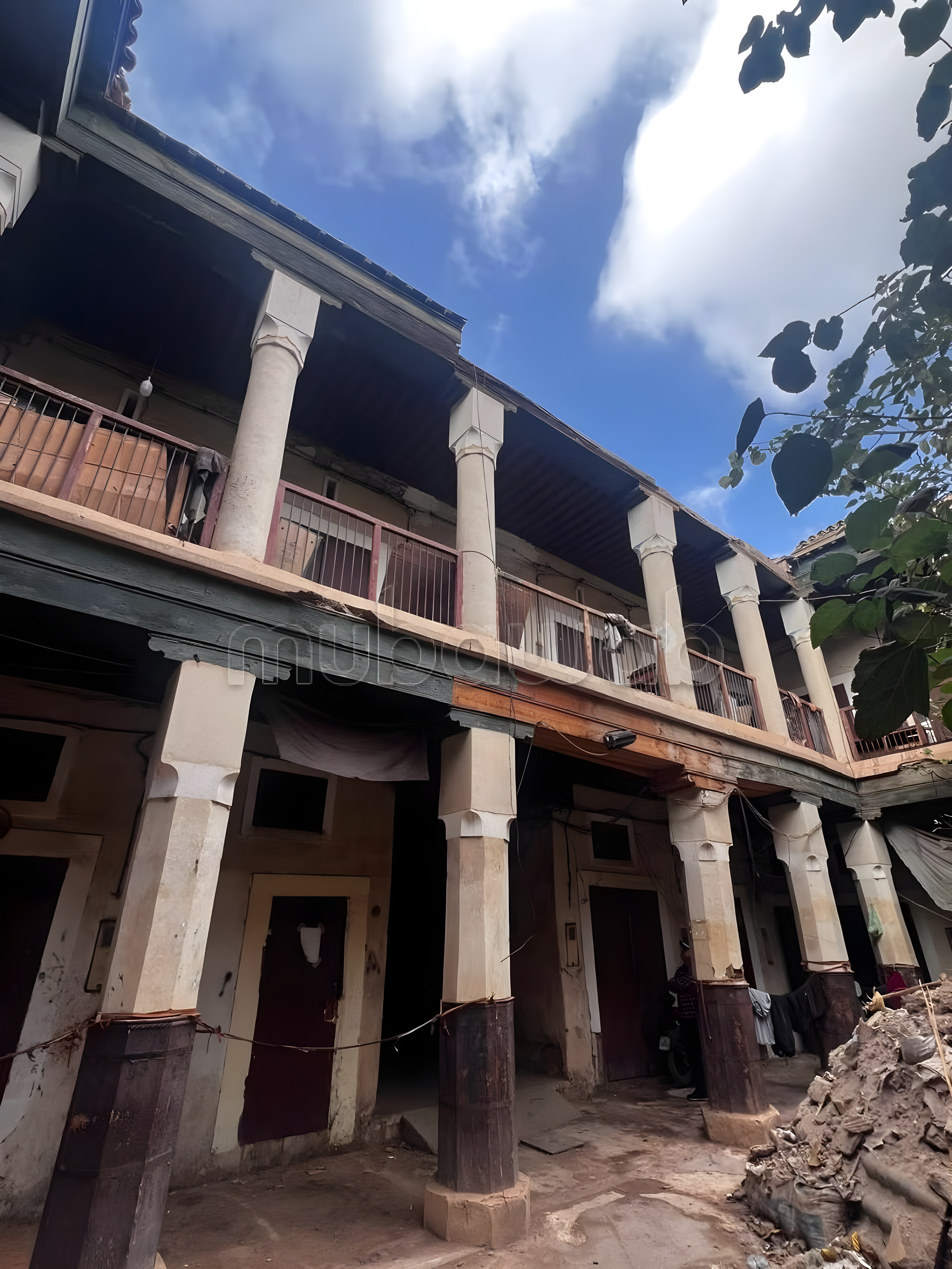 Unclear facade of a multi-story building in Kaat Ben Nahid with wooden elements and balconies.