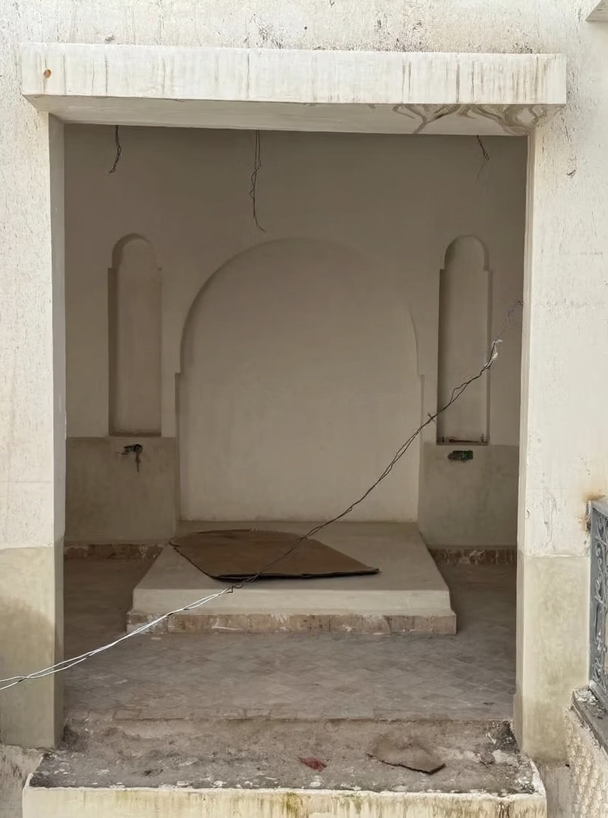 Facade of Essebtiyen guesthouse with arched design and visible wear.
