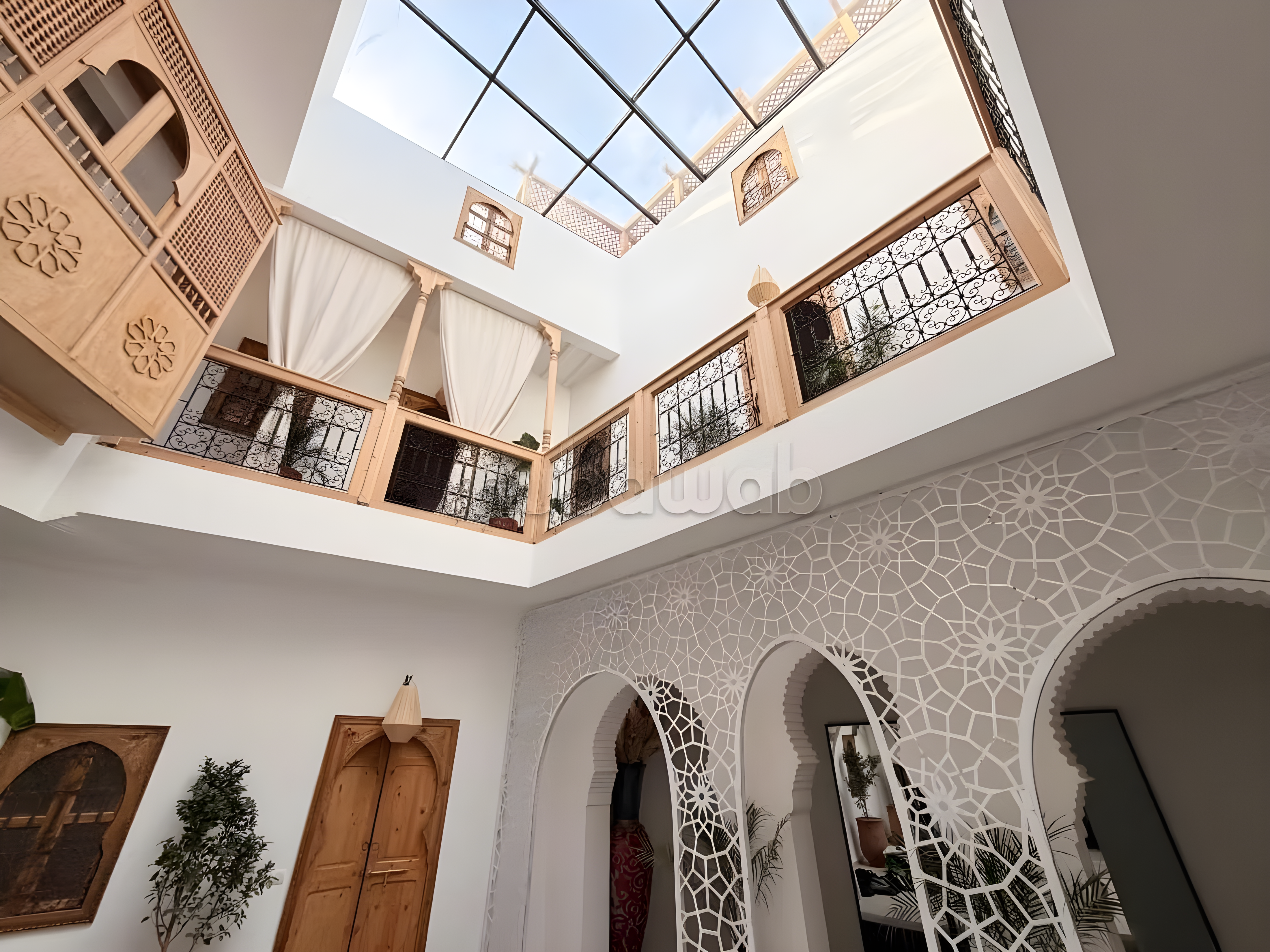 Courtyard with glass roof, wooden balconies, and Moroccan decor in Arset El Houta guesthouse.