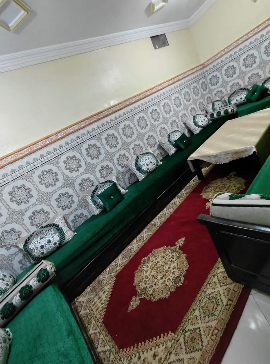 Moroccan salon with green seating, patterned tiles, and central table in Jnan Ben Chagra guesthouse.