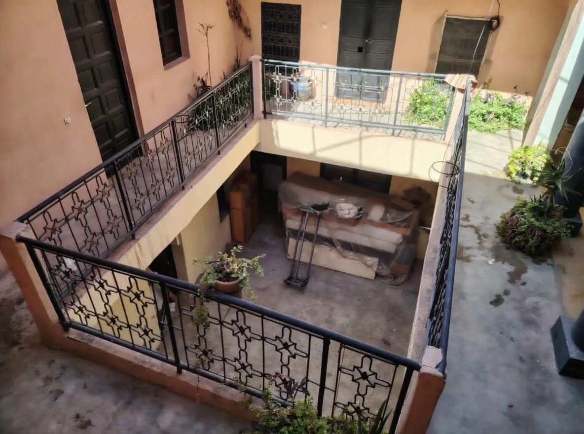 Riad courtyard with plants, seating area, and access doors in Rmila.