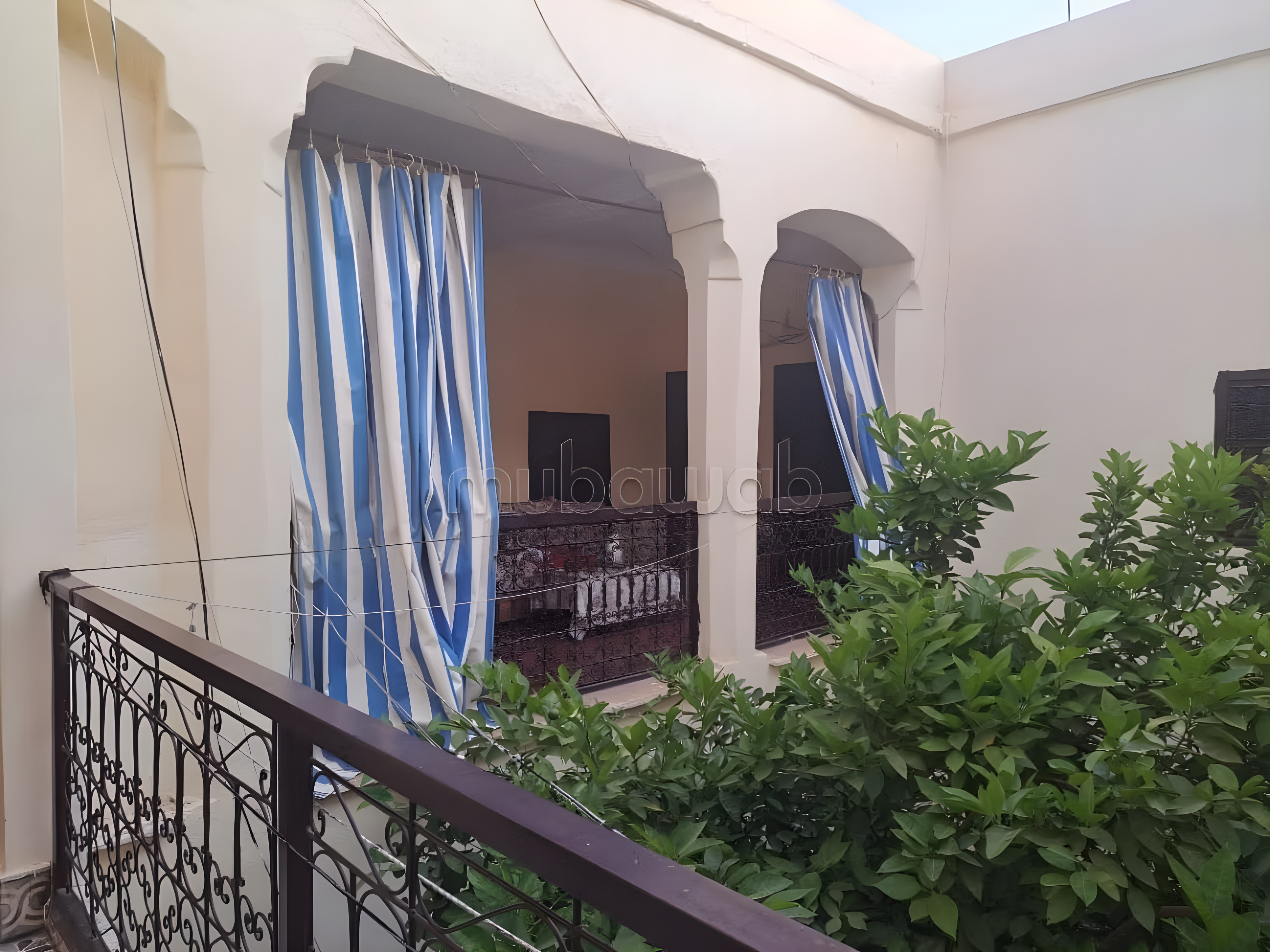 Terrace with metal railings and striped curtains in Arset Ihiri.