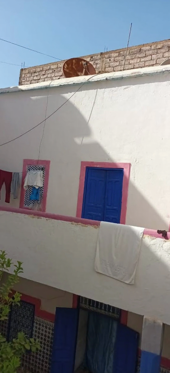 Facade of a Rmila guesthouse with white walls and colorful window frames.