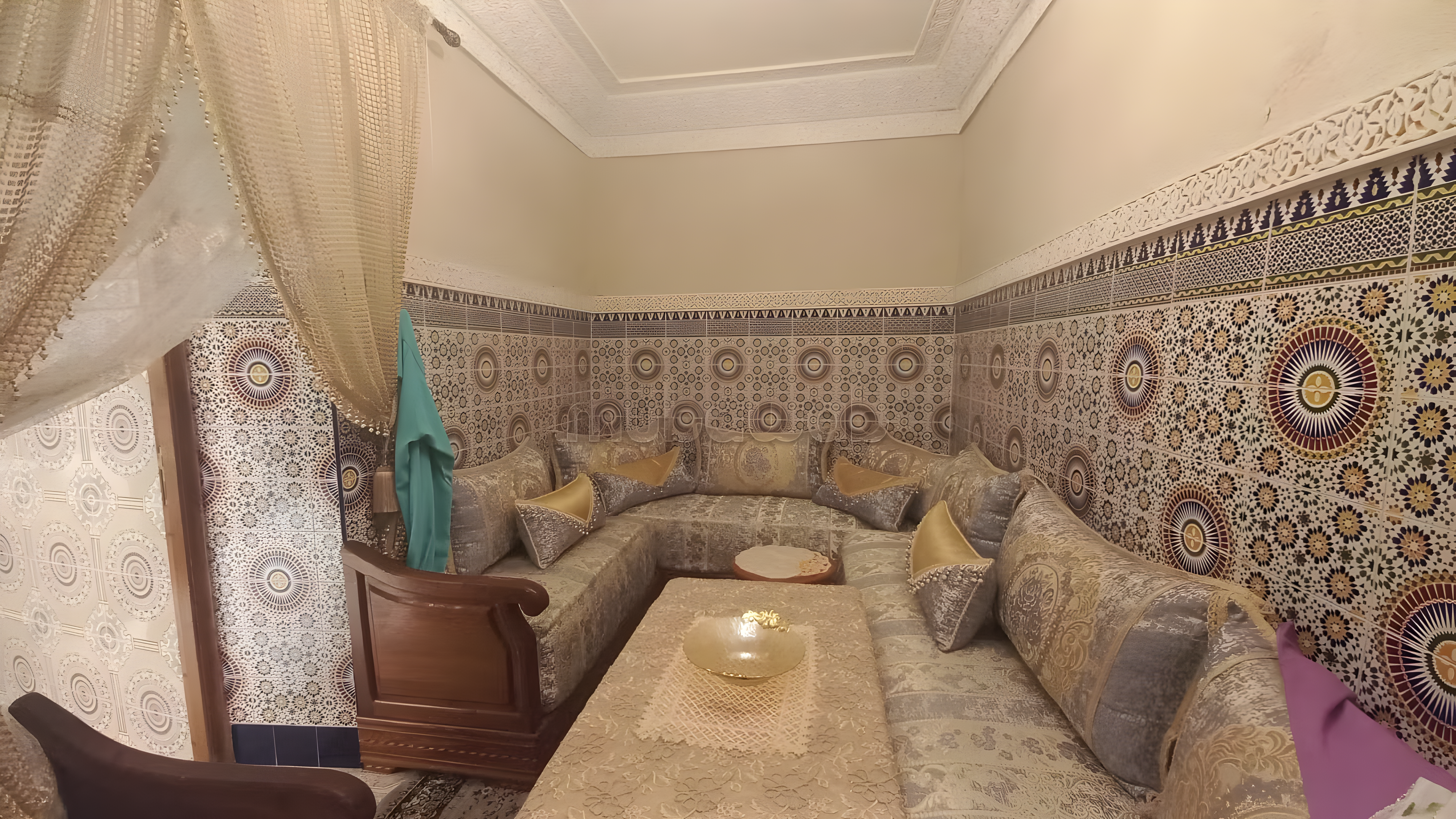 Traditional Moroccan salon with mosaic tile walls and seating in Sidi Bou Amar guesthouse.
