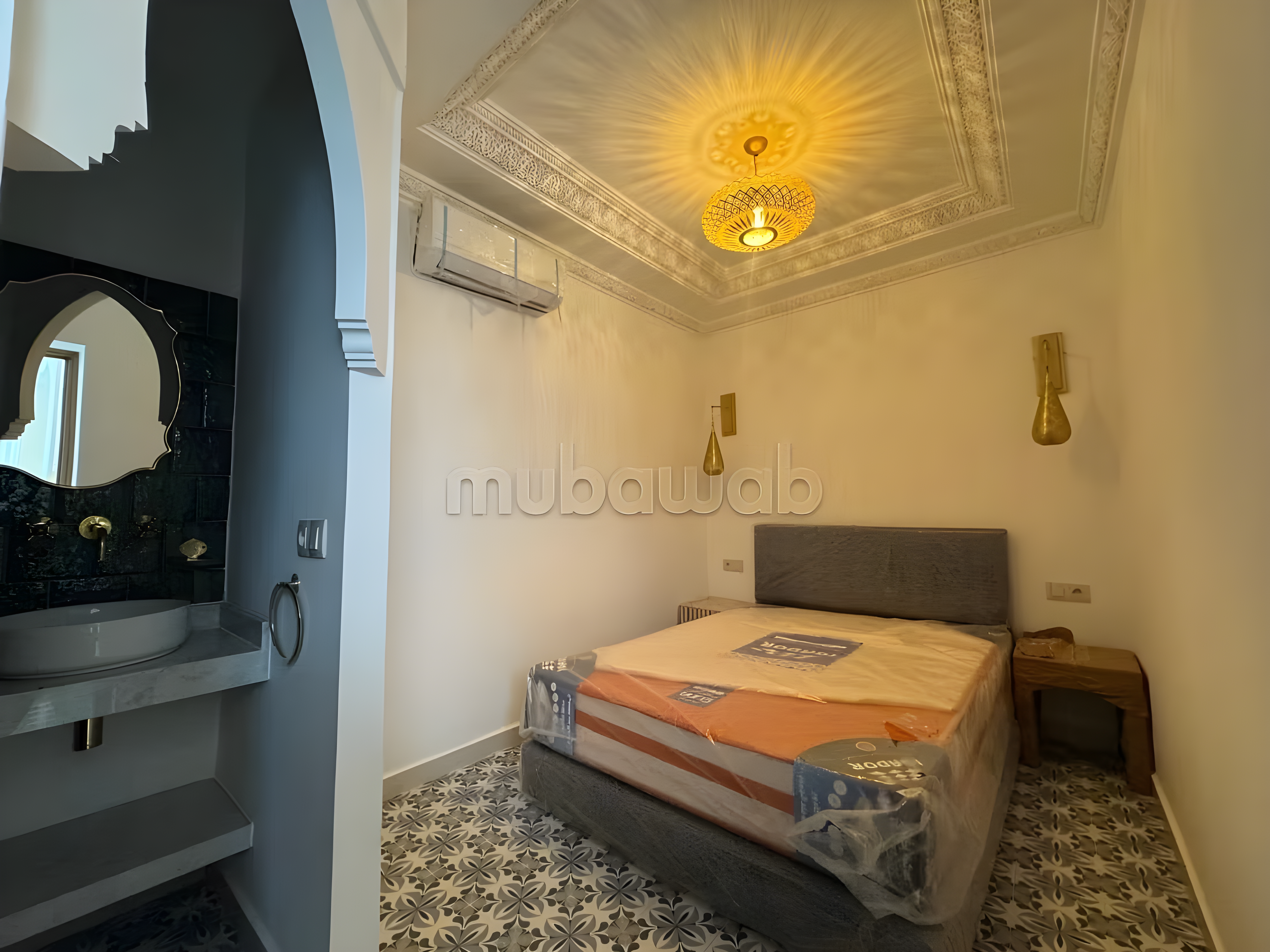 Guesthouse bedroom with patterned tiles and built-in sink in Michouar.