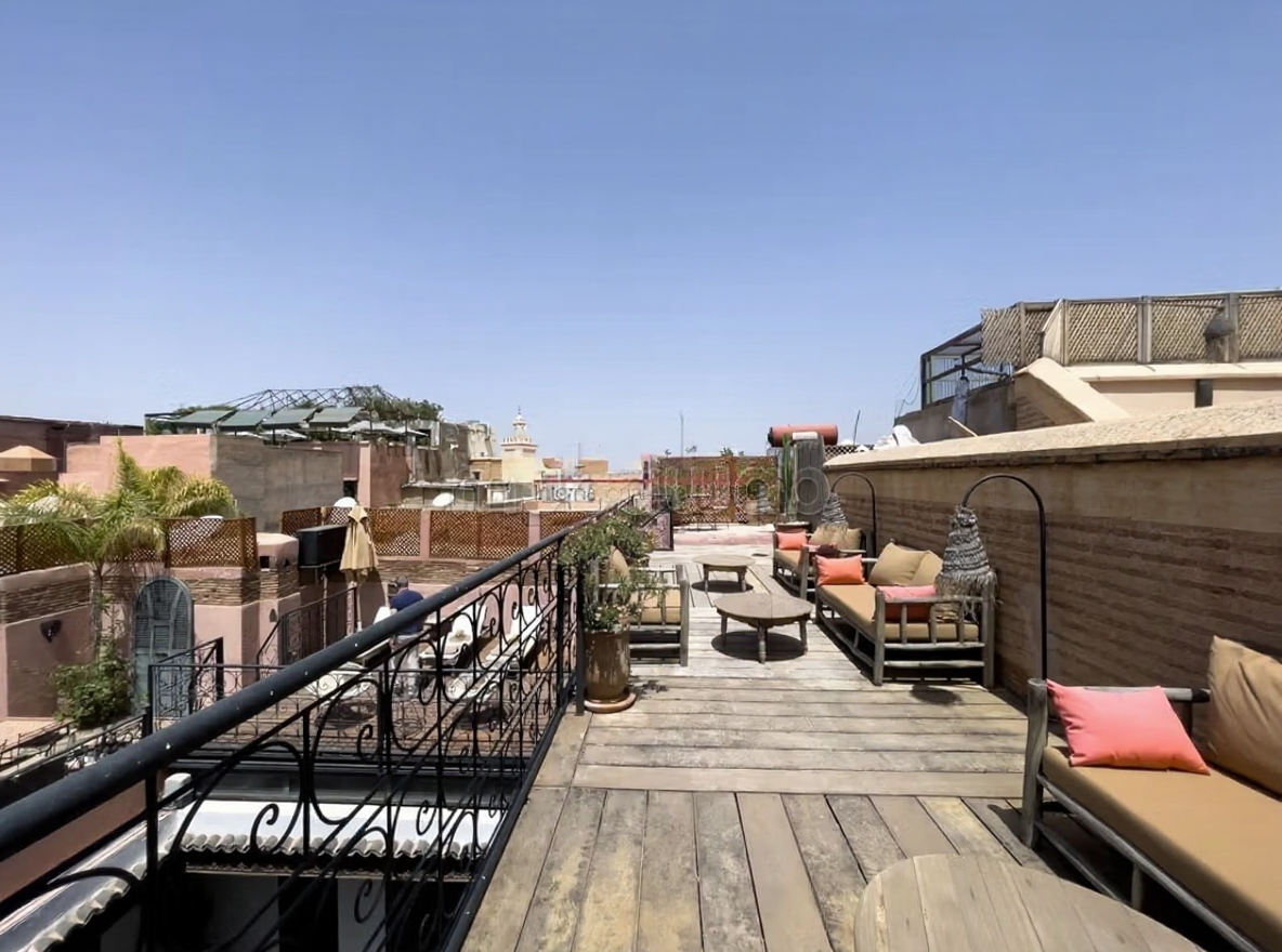 Rooftop view of a Rahba Kedima riad with seating and wooden flooring.