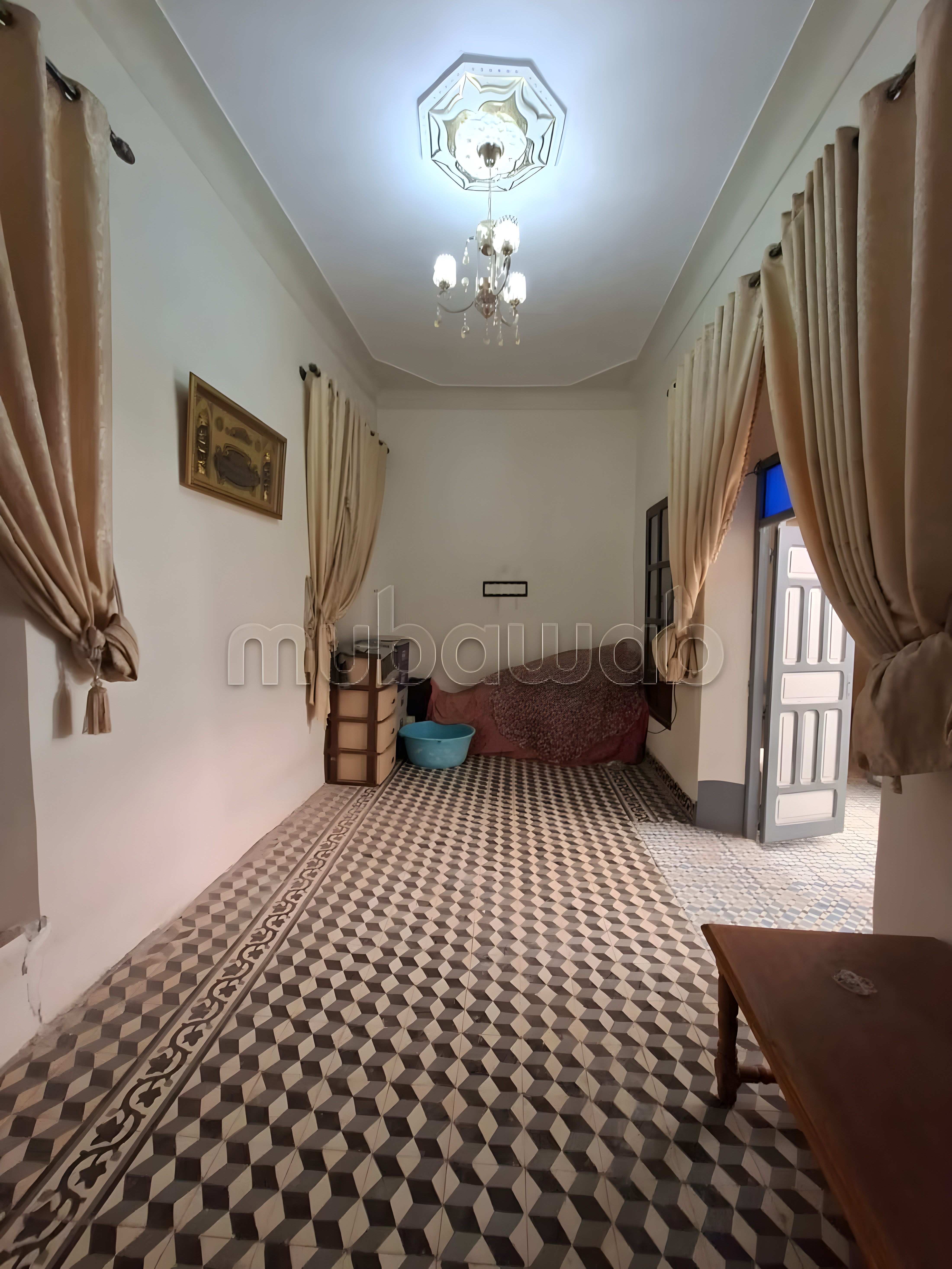 Salon with geometric tiled floor, curtains, and chandelier in Rahba Kedima.