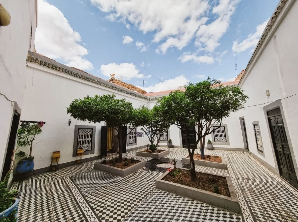 Courtyard with tiled floor and trees at a guesthouse in Arset Ben Chebli.