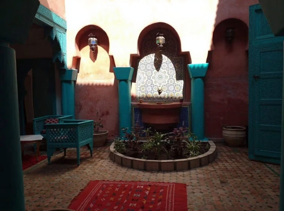 Courtyard with Moroccan tilework and colorful furniture in Sidi Bou Amar guesthouse.