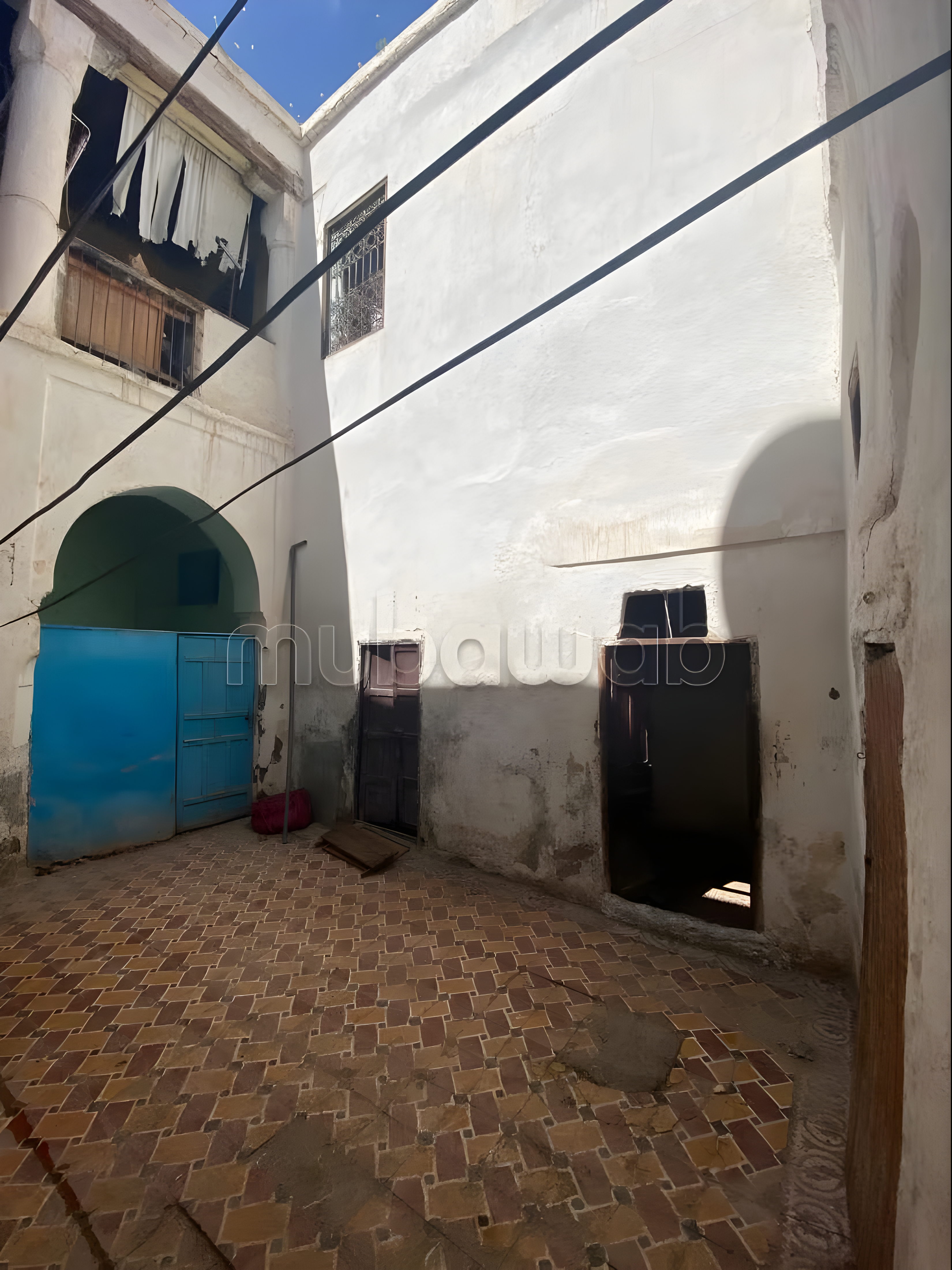 Courtyard in Arset El Maach with tiled flooring, clotheslines, and open sky.