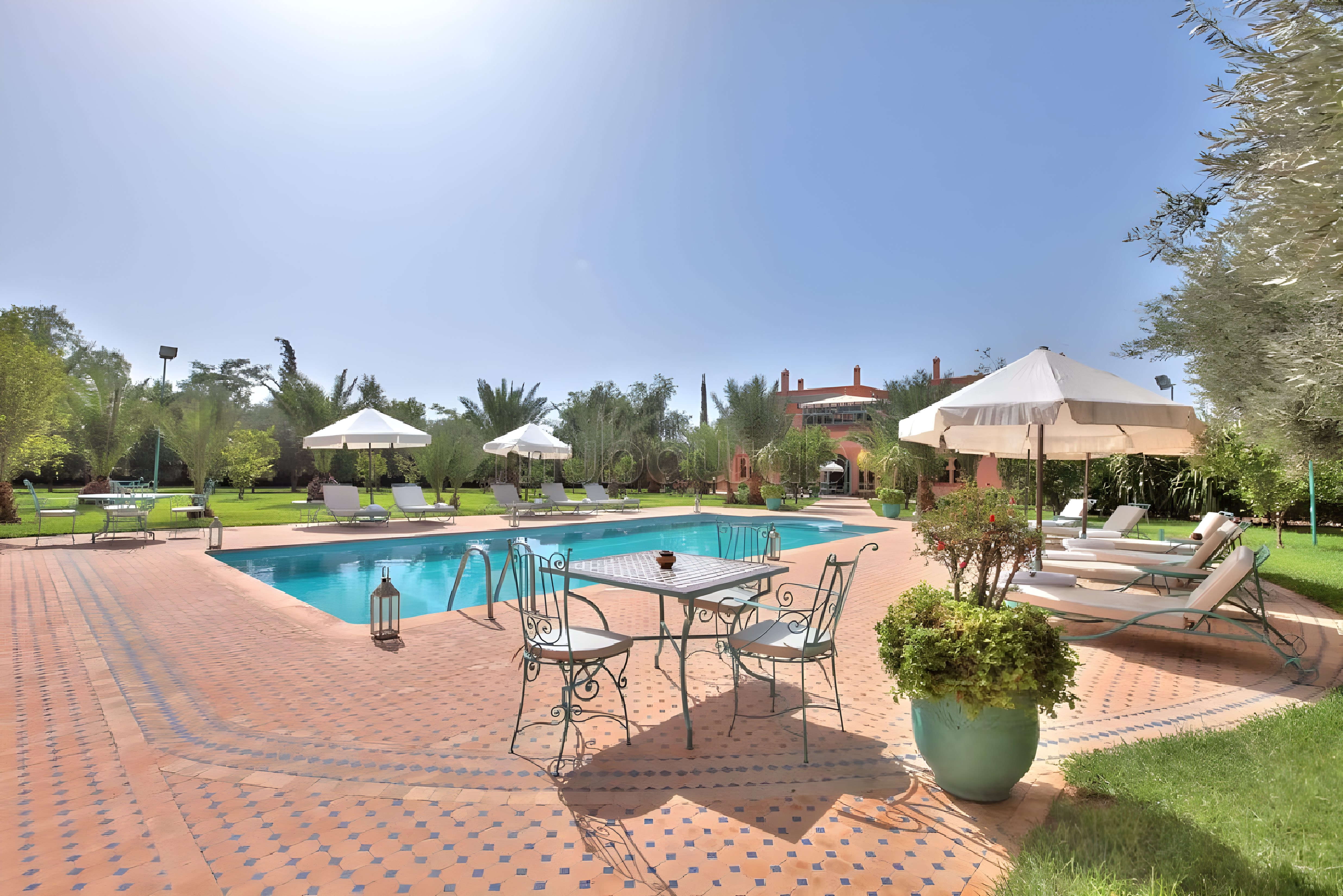 Courtyard with pool, umbrellas, and greenery in Ennakhil guesthouse.