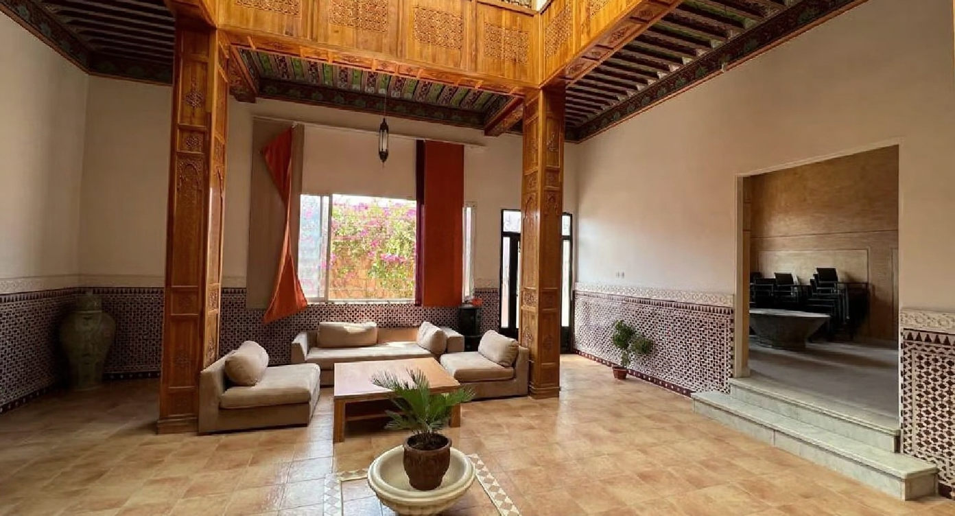 Moroccan salon with wooden decor and mosaic tiles, Ennakhil guesthouse.