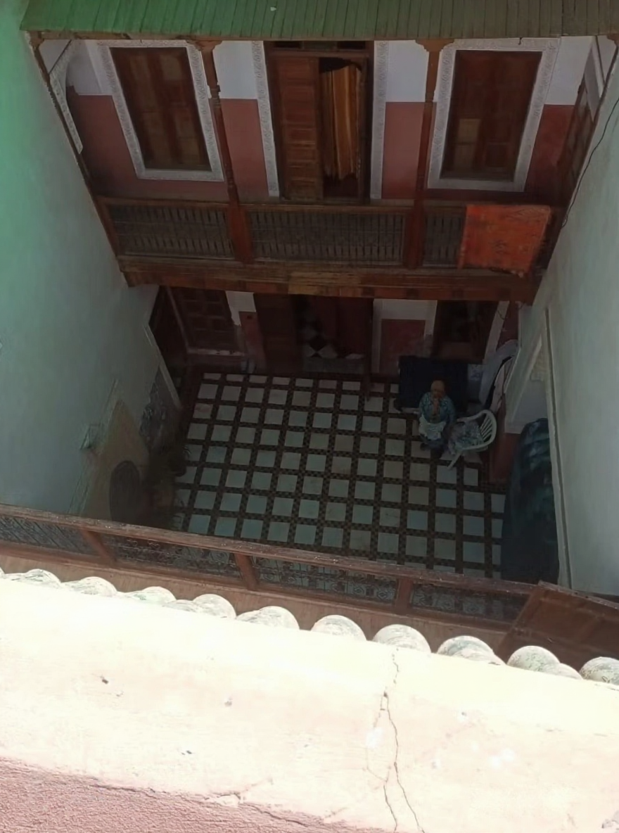 Courtyard with patterned tiles, wooden balconies, and multiple doorways in Mouassine.