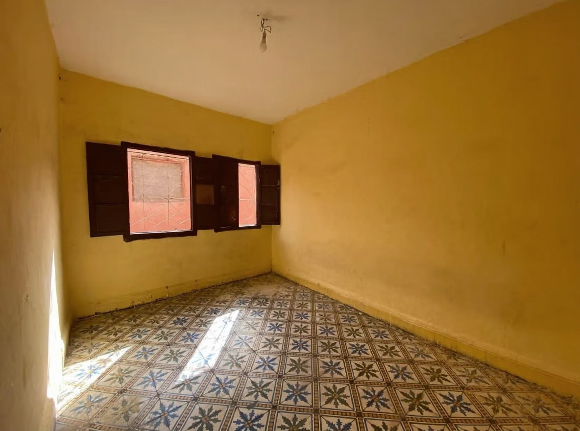 Yellow-walled bedroom with tiled floors and wooden shuttered windows.
