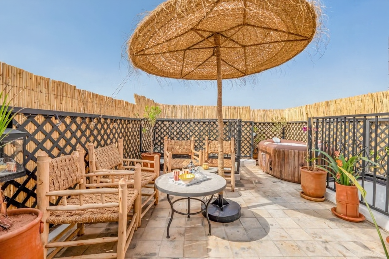 Rooftop seating with sunshade and hot tub at a guesthouse in Moulay Lyazid.