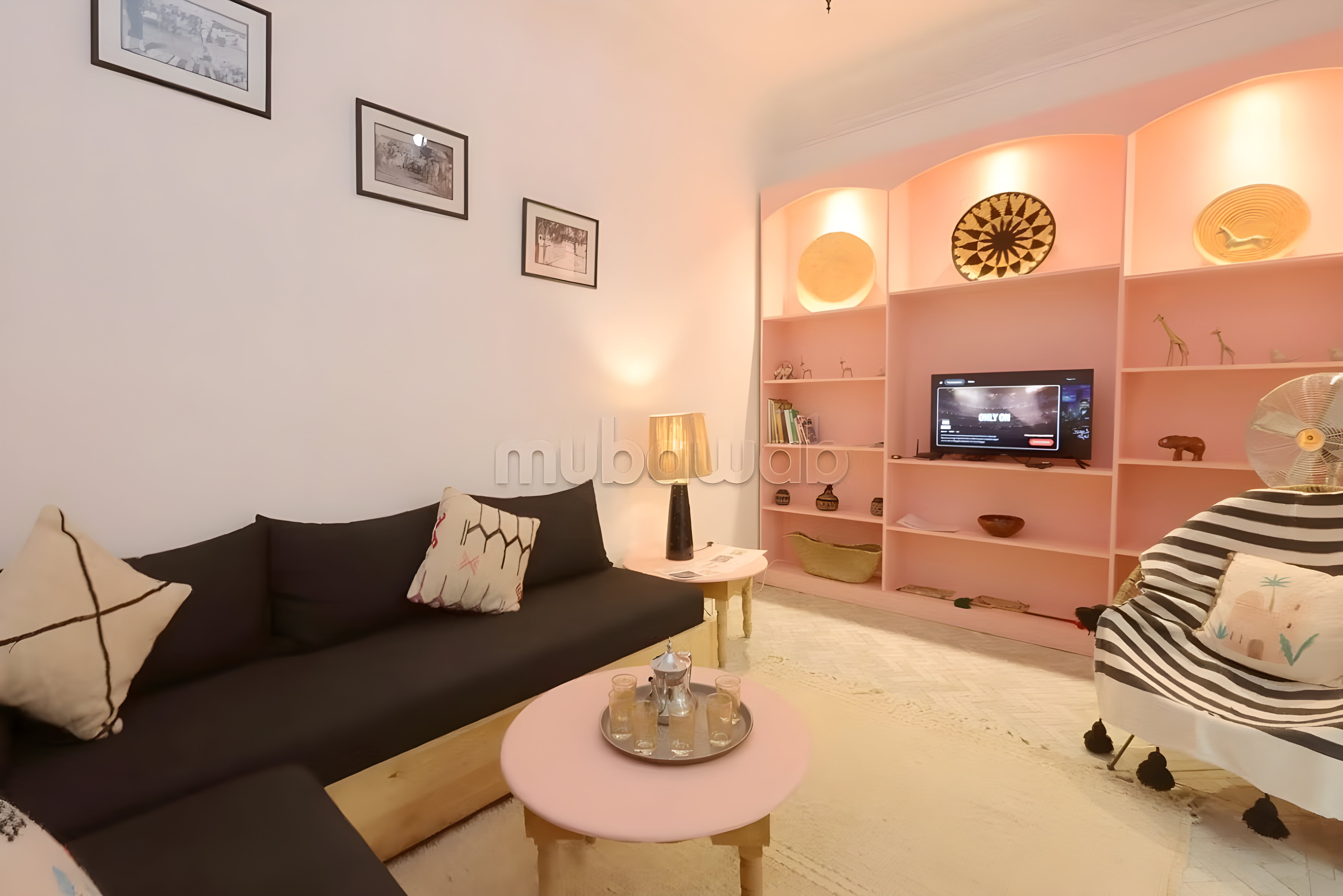 Salon with black couch, pink shelves, and round coffee table in Rahba Kedima guesthouse.