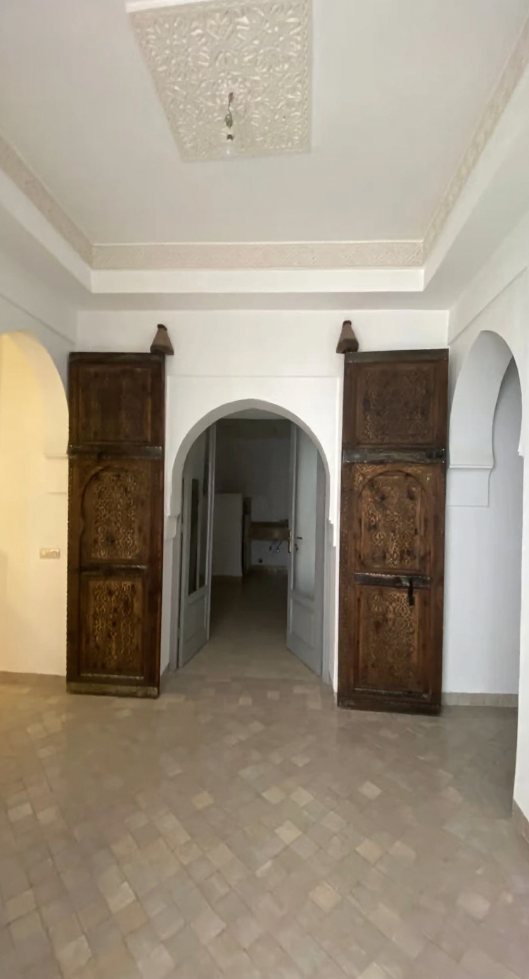 Traditional Moroccan salon with arched doorways and tiled flooring.