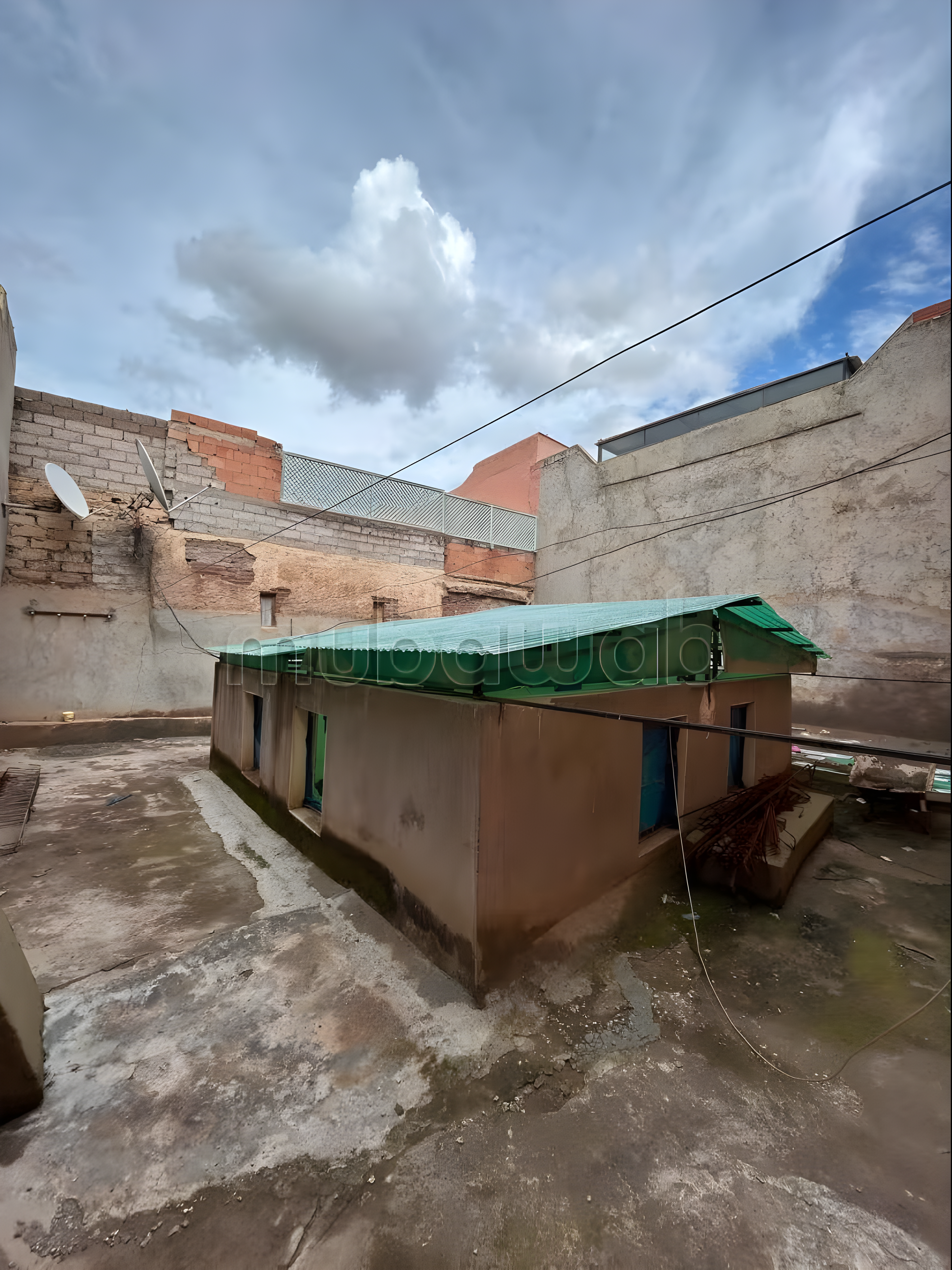 Rooftop area of Arset El Houta guesthouse with green cover and blue doors.