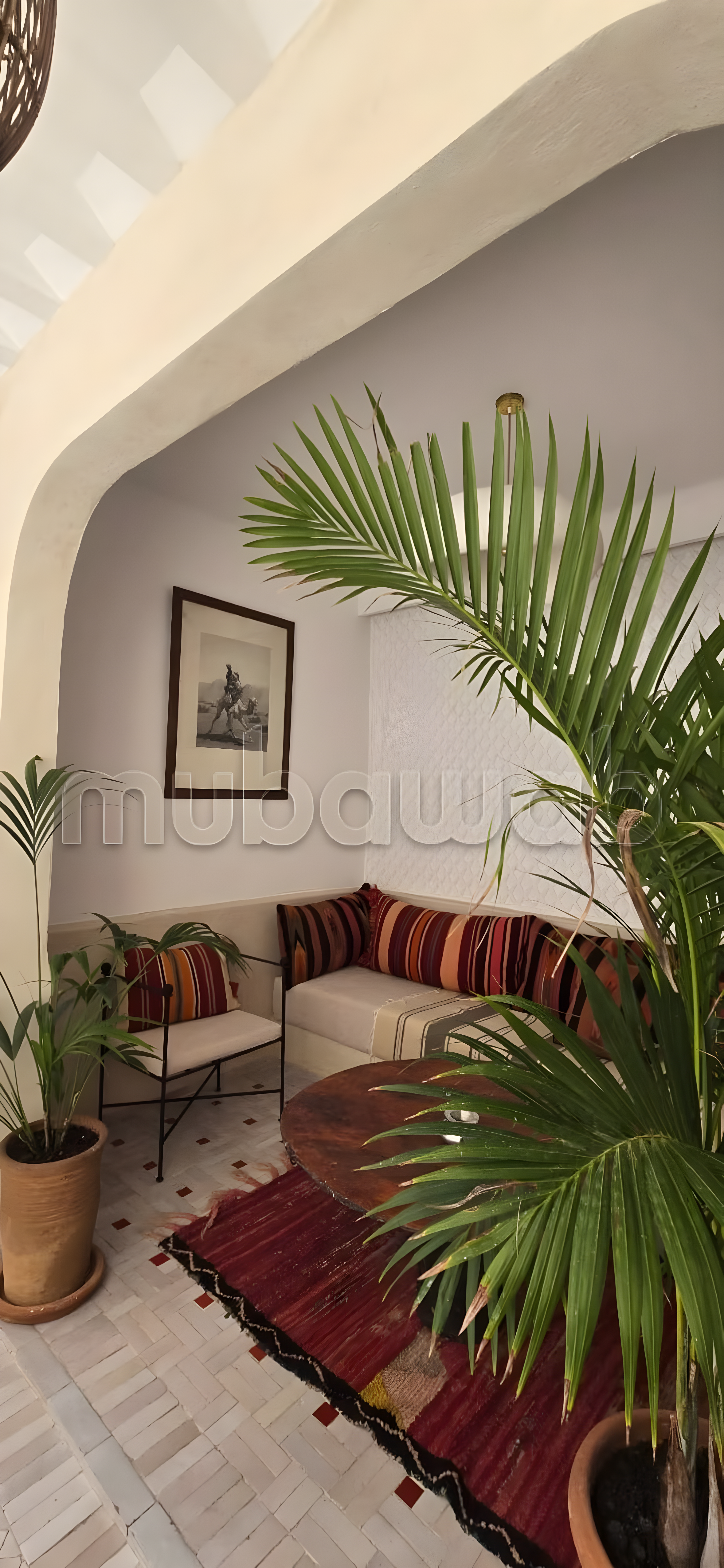 Salon with seating, potted plants, and wall-mounted artwork in Arset El Maach guesthouse.